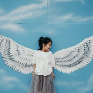 girl leaning on wall with wings mural painting